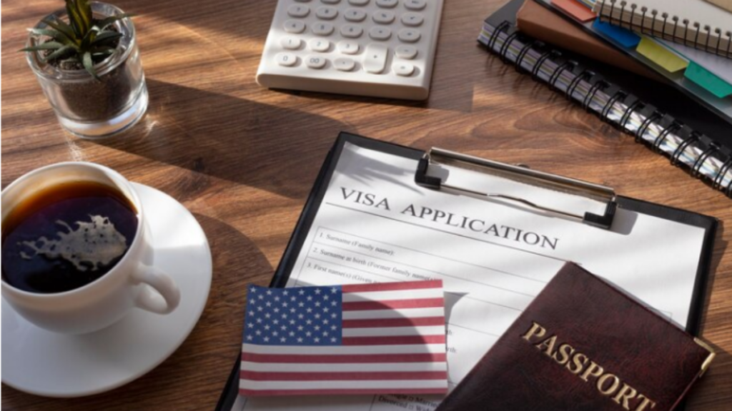 A picture showing black tea, calculator, US flag and a passport with some notebooks at the background.