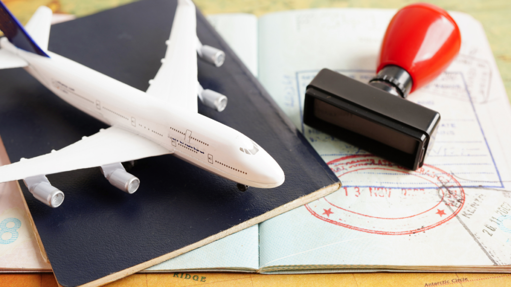 A picture of a passport and a tamp with a toy aeroplane placed on it.