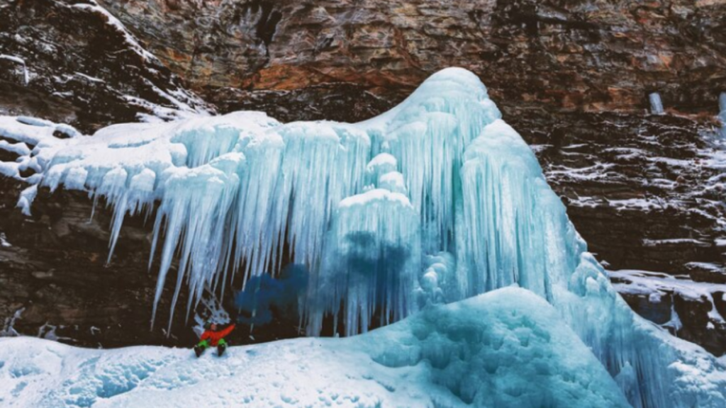 An image of Glacier National Park with ice-covered mountain with a person sliding on the ice.