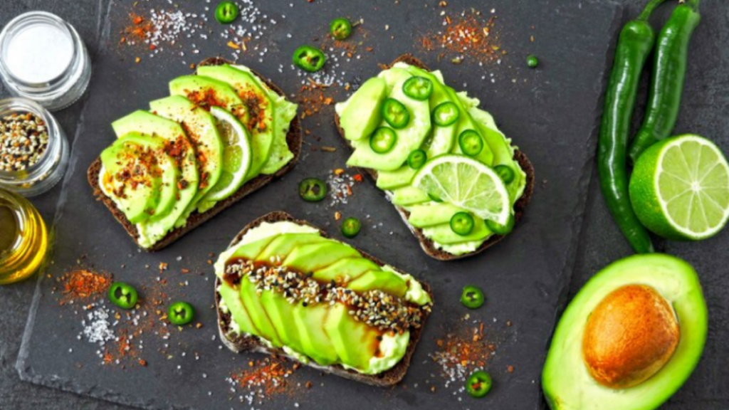 A picture of some vegetables including lemons, green chillies, avacado and some salts.